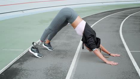Frau-Mit-Beinprothese-Macht-Yoga-Auf-Der-Rennstrecke.-Dame,-Die-Körper-Ausdehnt