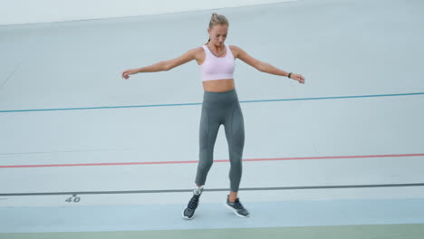Athlete-with-prosthetic-leg-jumping-sideways-on-track.-Girl-training-at-stadium