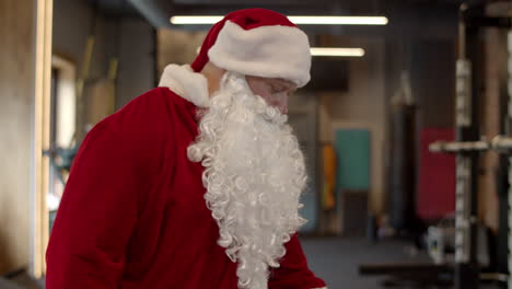 Serious-santa-man-walking-at-gym.-Sportsman-taking-off-clothes-in-sport-club
