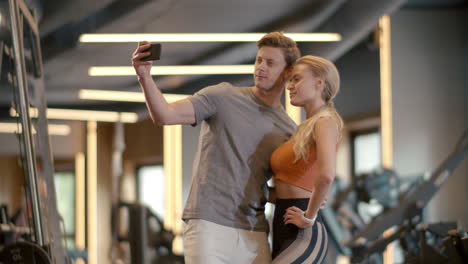 Smiling-couple-making-selfie-photo-at-gym.-Fit-man-taking-picture-in-sport-club