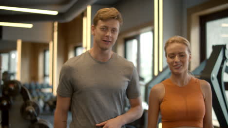 Smiling-couple-walking-at-gym.-Sport-man-and-woman-discussing-in-fitness-center