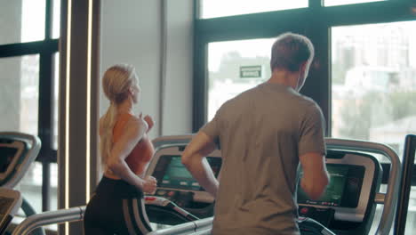 Sporty-fit-couple-doing-cardio-at-gym.-Family-running-on-treadmill-in-sport-club