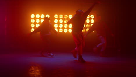 Three-hiphop-guys-breakdancing-on-nightclub-stage.-Dancers-performing-freestyle.