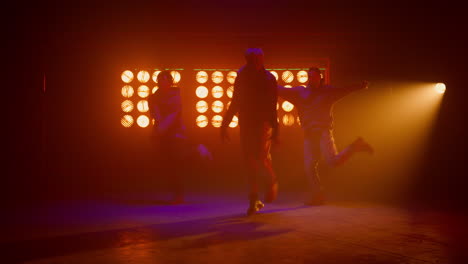 Team-dancers-enjoying-modern-dance-in-show-stage.-Sporty-men-performing-hip-hop