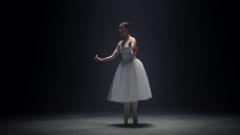 Beautiful-ballerina-dancing-on-tiptoe-indoors.-Ballet-dancer-rehearsing-on-stage