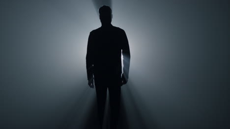 Silhouette-man-walking-in-darkness.-Male-person-going-straight-on-in-dark.