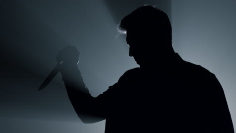 Silhouette-aggressive-criminal-attacking-with-knife,-Dangerous-man-using-weapon.