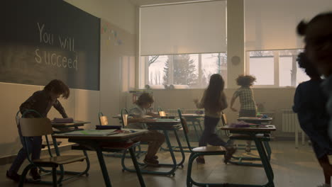 Positive-schoolchildren-running-in-classroom-after-break-at-elementary-school