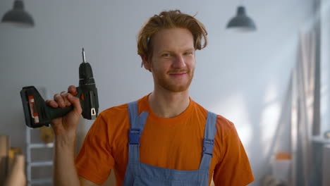 Cheerful-man-posing-with-screwdriver-in-new-apartment-during-home-repair.
