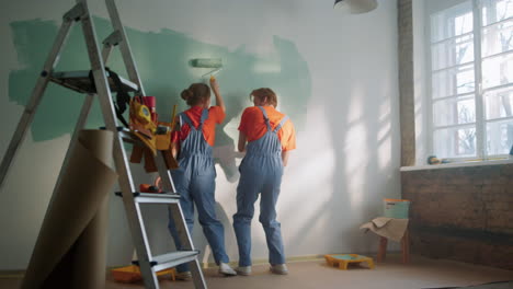 Happy-couple-painting-wall-indoors.-Family-dancing-during-decoration-in-home.