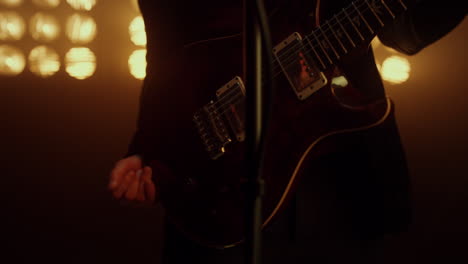 Professional-guitarist-holding-guitar-on-stage-close-up.-Man-performing-in-club.