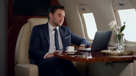 Serious-businessman-videocalling-partner-in-private-jet.-Focused-ceo-talk-online
