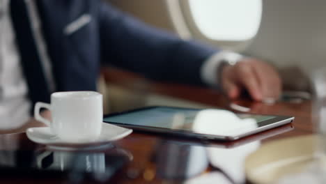 Hand-taking-coffee-cup-in-luxury-airplane-closeup.-Successful-manager-resting