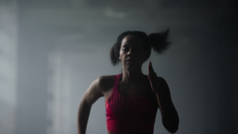 Sporty-girl-jogging-in-gym.-Woman-running-fast-in-dark-corridor-of-loft-building