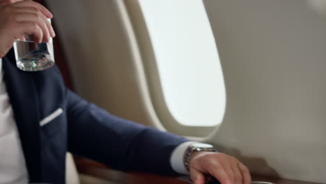 Businessman-drinking-fresh-water-on-airplane-trip.-Closeup-hand-taking-glass