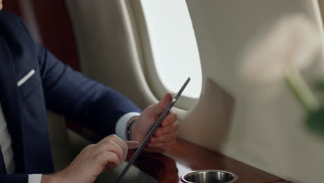 Focused-investor-working-tablet-in-private-jet.-Closeup-man-hands-touching-pad