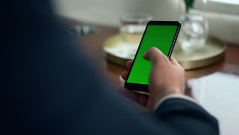 Hand-holding-chroma-key-smartphone-closeup.-Manager-touching-phone-green-screen
