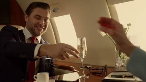 Business-people-shaking-hands-on-private-jet-closeup.-Corporate-team-celebrating