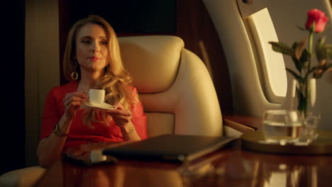 Attractive-woman-enjoying-coffee-in-golden-sunlight.-Luxury-lady-rest-airplane