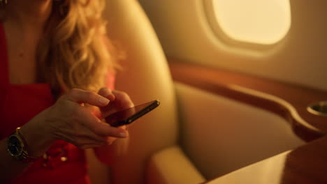Businesswoman-typing-message-smartphone-closeup.-Passenger-flying-private-jet