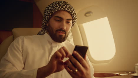 Hombre-Rico-Mirando-Teléfono-Inteligente-En-Primer-Plano-De-Viaje.-Pantalla-Táctil-árabe-Sonriente