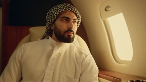 Closeup-young-arabian-looking-camera-in-muslim-clothing.-Smiling-man-rest-at-jet