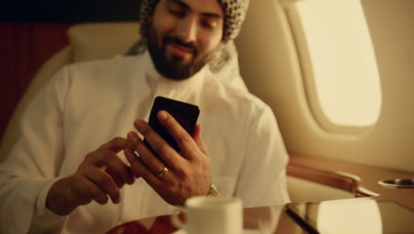 Fröhlicher-Araber,-Der-Auf-Geschäftsreise-Sein-Smartphone-Wischt.-Nahaufnahme-Eines-Mannes,-Der-Sein-Telefon-In-Die-Hand-Nimmt