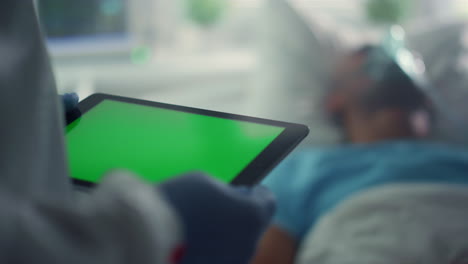 Doctor-using-pad-chroma-key-screen-closeup.-Patient-oxygen-mask-in-hospital-bed