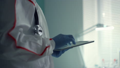 Portrait-doctor-holding-tablet-computer-in-medical-protective-suit-hospital-ward