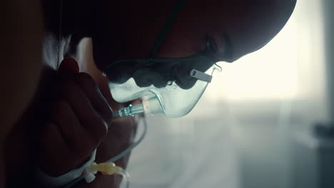 Male-patient-in-oxygen-mask-breathe-crossing-arms-in-intensive-care-unit-closeup