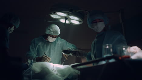 Ärzteteam-Führt-Chirurgische-Operation-Im-Dunklen-Operationssaal-Des-Krankenhauses-Durch.