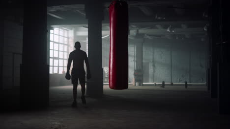 Man-in-boxing-gloves-walking-in-loft-building.-Athlete-doing-boxing-training