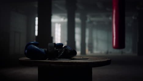 Box-sport-concept.-Blue-boxing-gloves-lying-on-wooden-box-in-gym