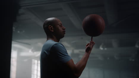 Porträt-Eines-Ernsthaften-Basketballspielers,-Der-Im-Fitnessstudio-Einen-Basketballball-Am-Finger-Dreht