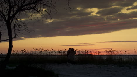 Ein-Paar-Geht-Am-Strand-Bei-Sonnenuntergang-Spazieren-Und-Verbringt-Gemeinsam-Zeit-In-Der-Natur-Der-Küstenlandschaft