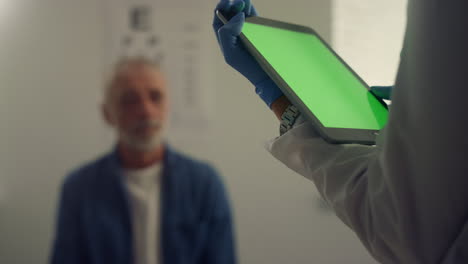 Green-screen-tablet-holding-doctor-hands-close-up.-Unknown-doctor-looking-pad.