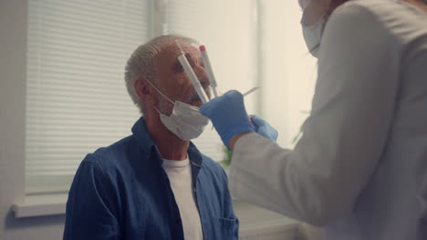 Nurse-taking-nasal-swab-covid-test-in-elderly-man-closeup.-Patient-on-checkup.