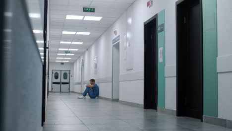 Medicine-worker-sitting-floor-ambulance-hallway.-Medic-resting-after-surgery.