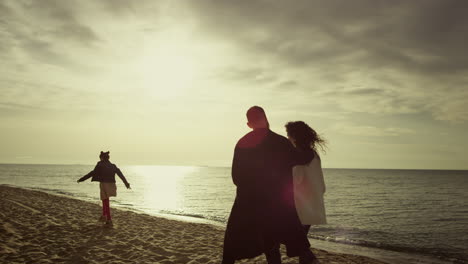Relaxed-family-walking-sand-beach-at-sunset-sky-nature.-People-enjoy-sea-view.