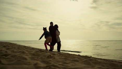 Family-enjoy-sunset-beach.-Playful-kid-girl-running-around-parents-at-sea-shore.