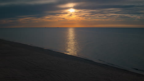 Luftaufnahme-Des-Strandes-Mit-Atemberaubenden-Sonnenuntergangsreflexionen-Im-Meer.-Ruhiger-Meerblick.