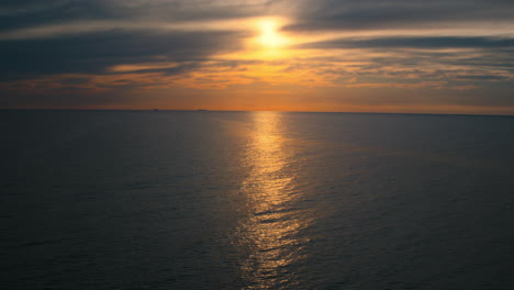Ocean-surface-against-peaceful-cloudy-sky-with-yellow-sun.-Ocean-reflecting-sun.