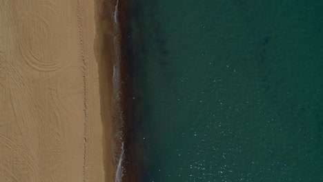 Ruhiger-Blick-Auf-Den-Sandstrand-Mit-Glatter-Meeresoberfläche-An-Einem-Warmen,-Sonnigen-Morgen.