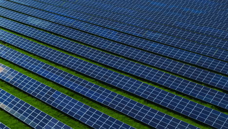 Aerial-view-photovoltaic-panels-park-on-green-field.-Blue-sky-reflecting