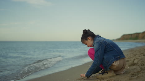 Child-playing-beach-sand-at-sea-family-trip.-Small-girl-spend-time-alone-outside
