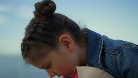 Shy-kid-sitting-beach-at-sea-background.-Little-girl-face-looking-down-on-nature