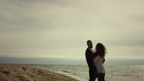 Couple-standing-sea-beach-in-casual-clothes.-Lovers-hugging-on-holiday-trip.