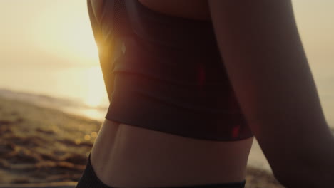 Sporty-woman-sitting-lotus-position-practicing-yoga-asana-at-sunset-close-up.