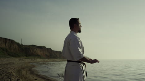 Athlete-making-meditation-exercise-on-beach.-Karate-fighter-perfecting-technique
