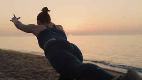 Slim-girl-practicing-warrior-asana-at-sunset.-Woman-making-yoga-exercise-on-sand